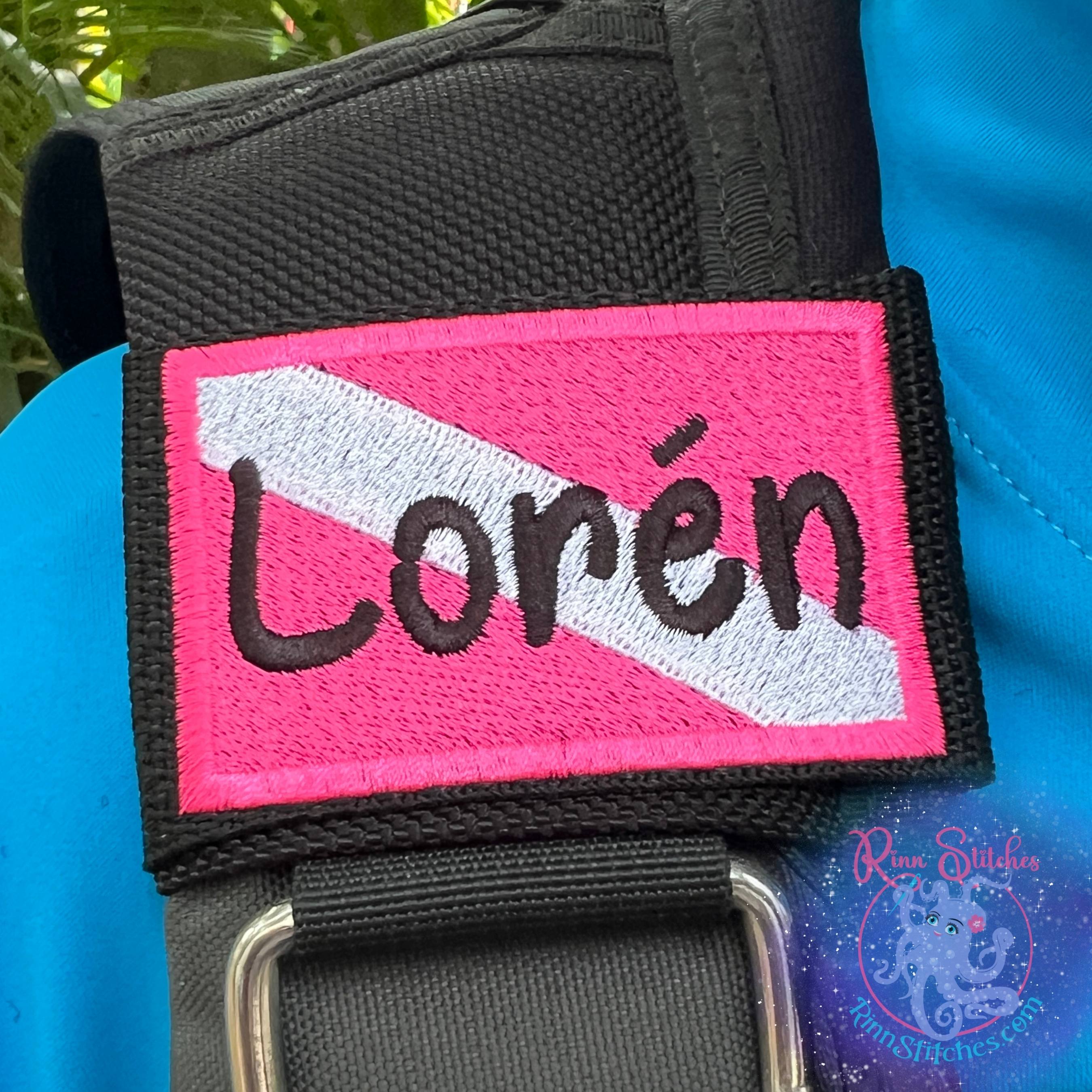 Standard size Dive Flag BCD tag Neon Pink and  White personalized with the name Loren in black thread and our popular Sand Castle Font embroidered on a 3 inch BCD strap - Scuba Gear Accessories - Maui Made - Rinn Stitches